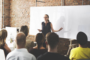 Woman teaching a crowd of people about supply chain