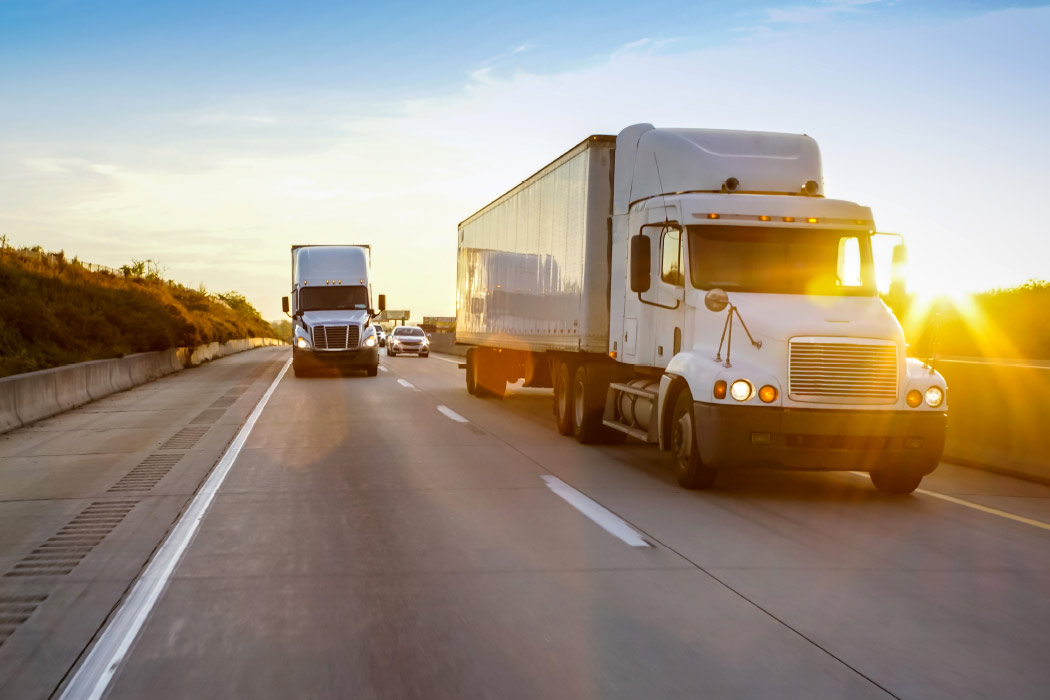2 trucks on freeway at sunrise