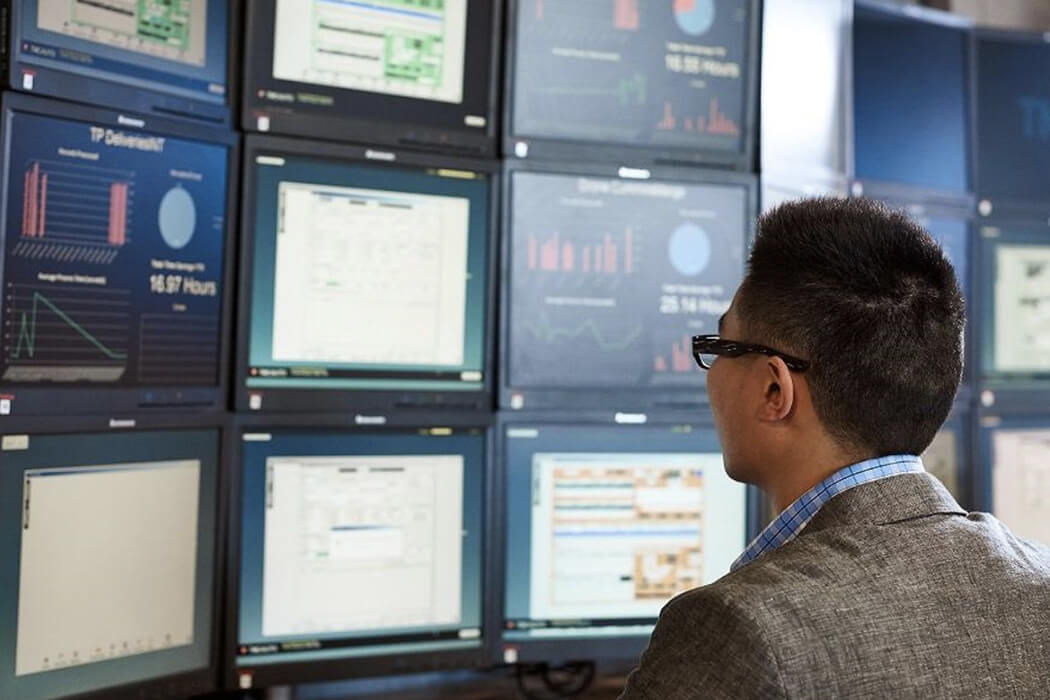 Man looking at 9 computer screens at once