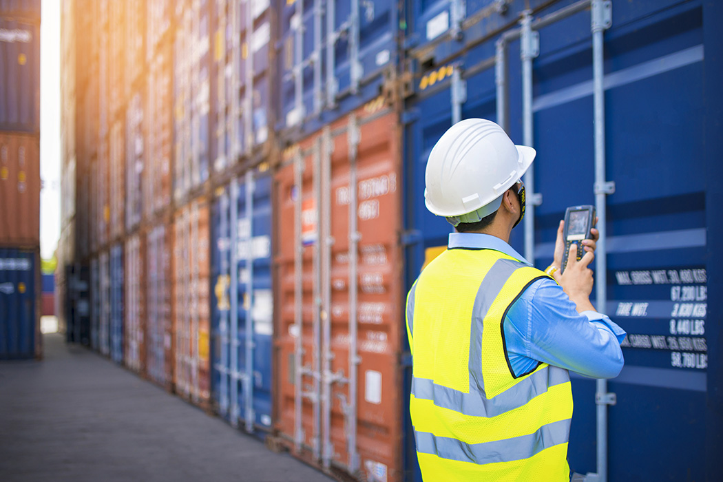 Port employee examining shipping containers
