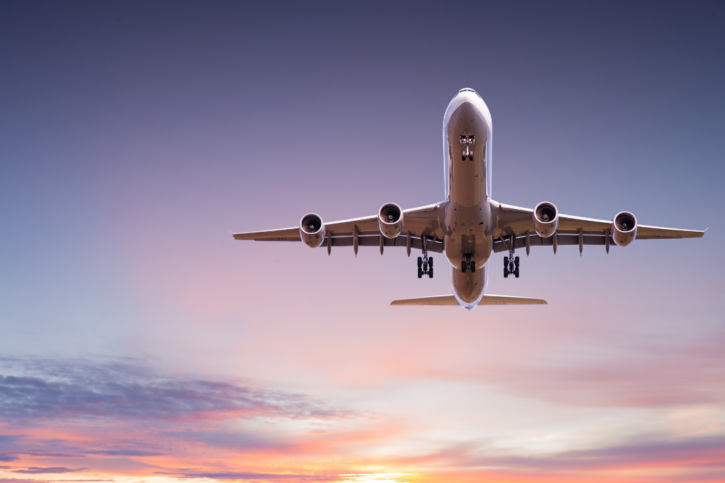 Underside view of air freight plane flying in sunset sky